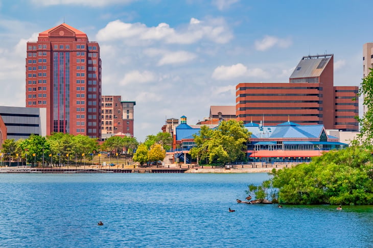 Downtown Toledo Ohio is filled with multi colored architecture that sits alongside the Maumee River. Ducks float in the water and sit on the island.