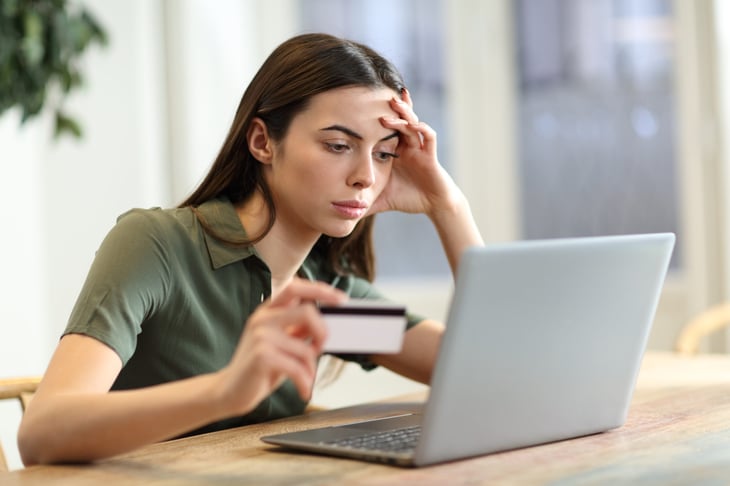 Worried or unhappy woman at her laptop, shopping online with a credit card