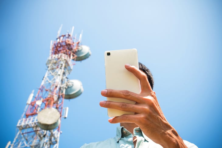 Man using phone with cell tower behind him.