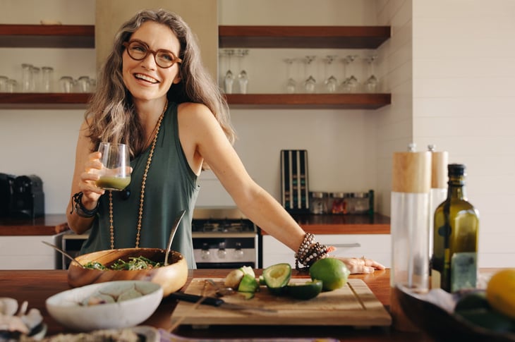 Woman cooking a healthy meal and drinking juice.