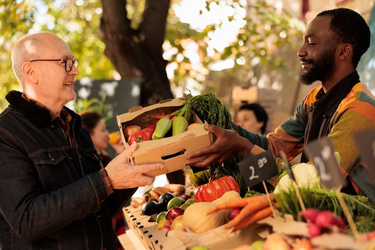 A man buying a box of fresh fruits and veggies at farmers market