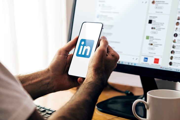 Man holding a smartphone with the LinkedIn app open on the screen.