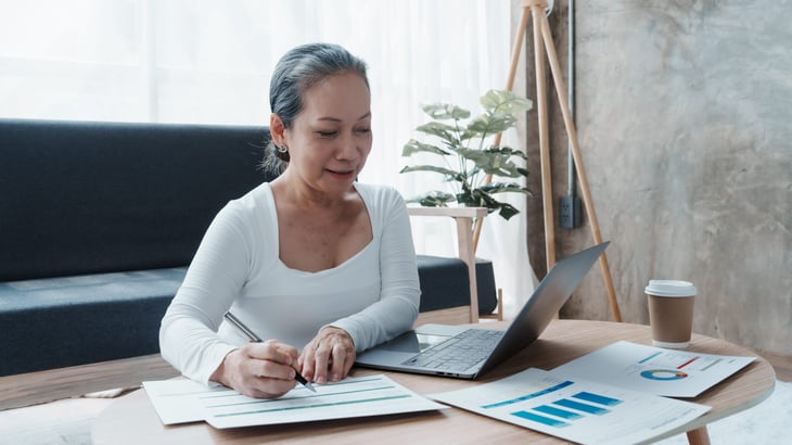 Mature businesswoman working with laptop, doing paperwork in an office workplace