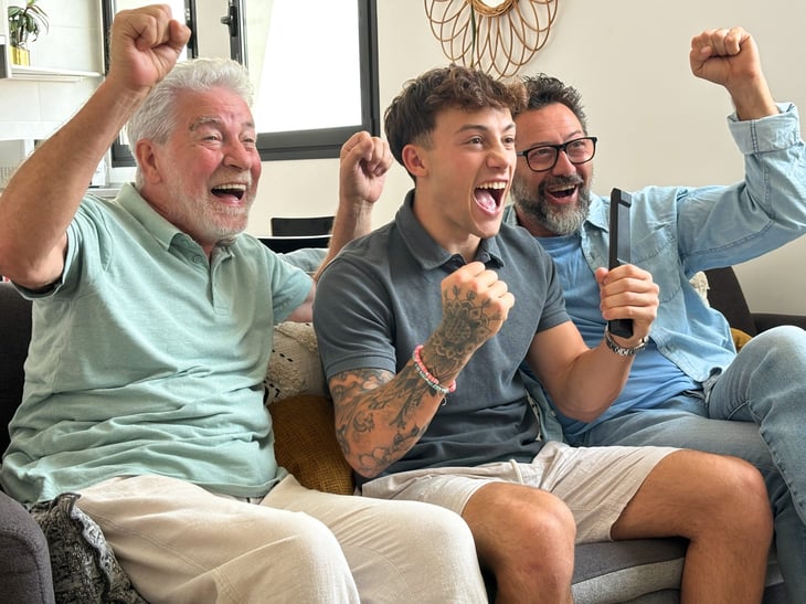 Enthusiastic three generations of men watch TV