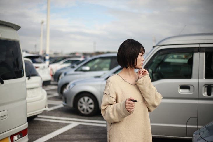 A woman looking for a car in a parking lot