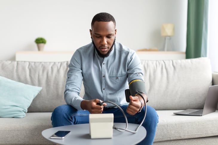Man measuring his blood pressure at home using a cuff.