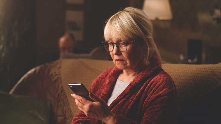 Older woman scared on the phone with a scammer.