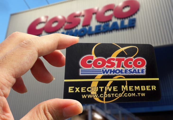 Holding up a Costco Executive Membership card in front of a store.