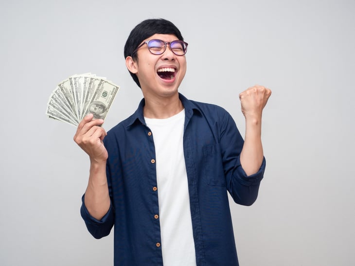 Happy man holding money with his fist up