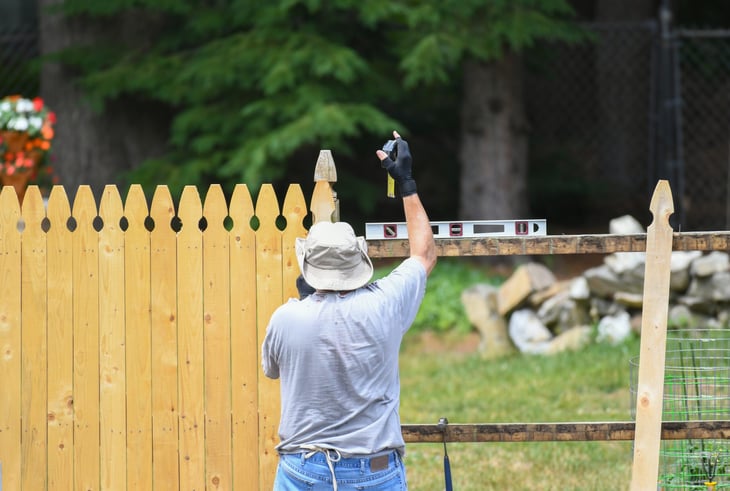 A manual worker installing a wooden fence
