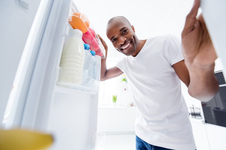 Happy man looking into fridge