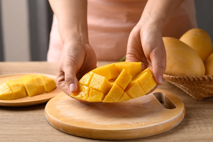 Someone holding a cut mango.