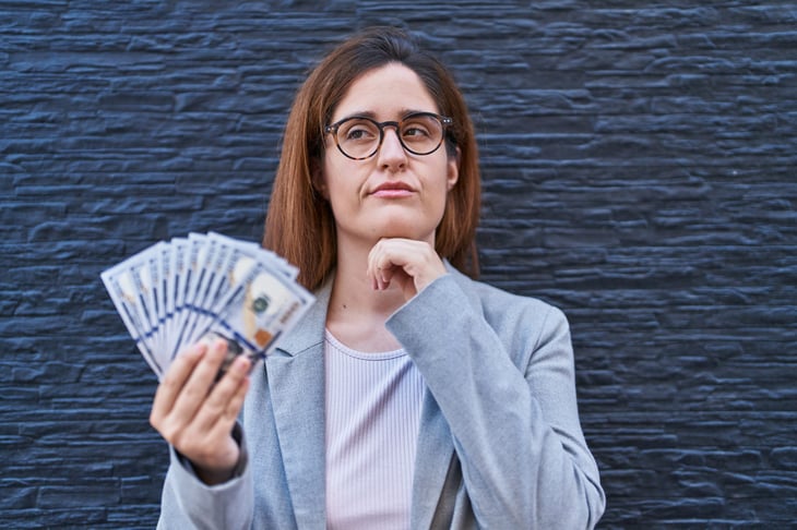 Woman holding money and thinking