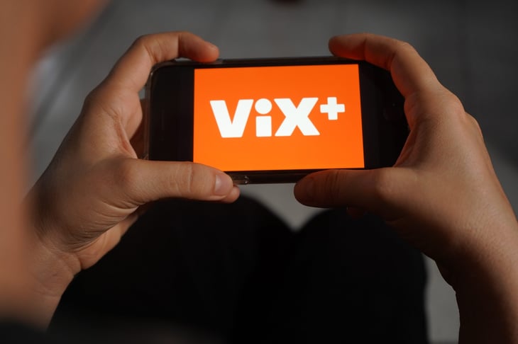 Vix+ logo streaming platform on a smartphone. Woman holding iPhone.