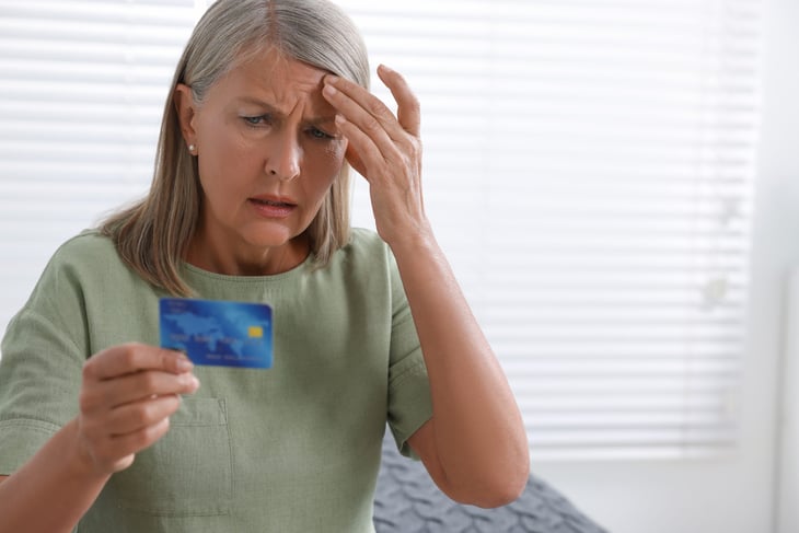 Upset senior woman looking at a credit card