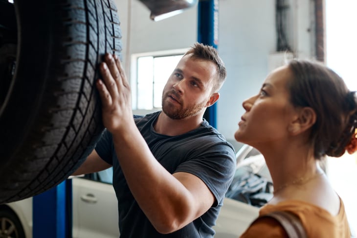 Customer and mechanic look at a car's tires