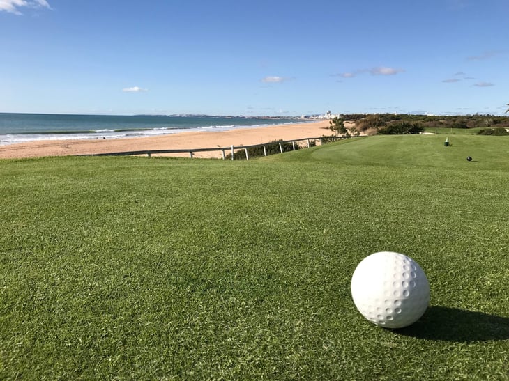 Golf ball on a golf green in Portugal, with the beach in the background.