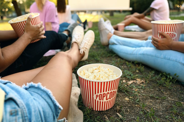 people with popcorn watching movie in open air cinema
