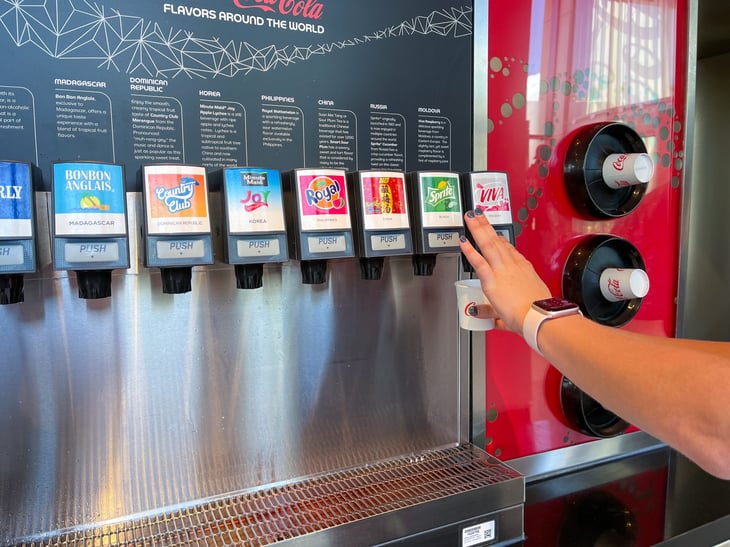 A person pouring a sample of soda from Club Cool at Disney World