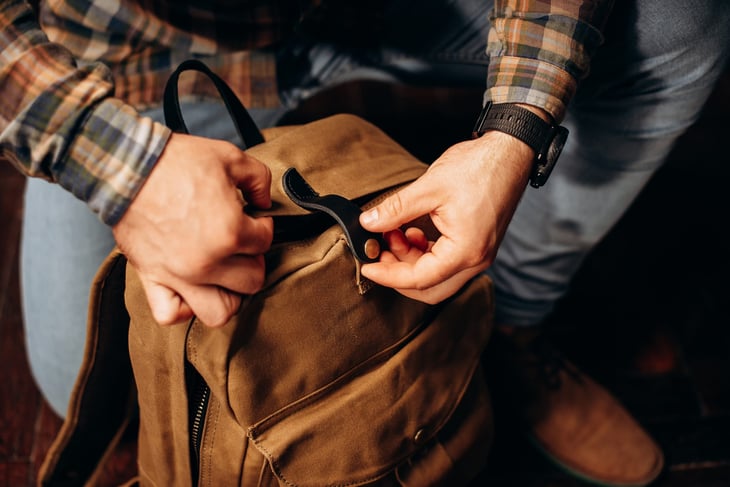 A man closes a canvas backpack