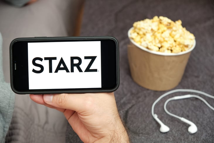 Starz logo on the mobile phone screen with popcorn box and Apple earpods