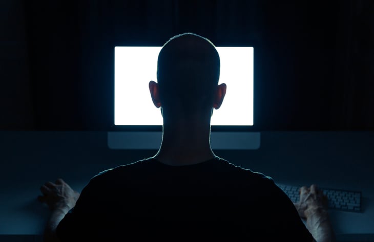 Man on the computer in a dark room.