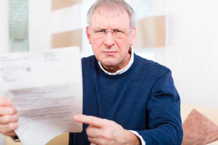 Unhappy senior pointing at a bill or letter