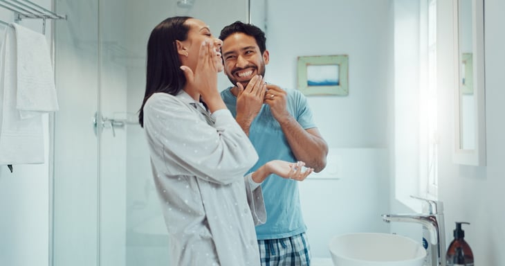 Couple laughing in bathroom together.