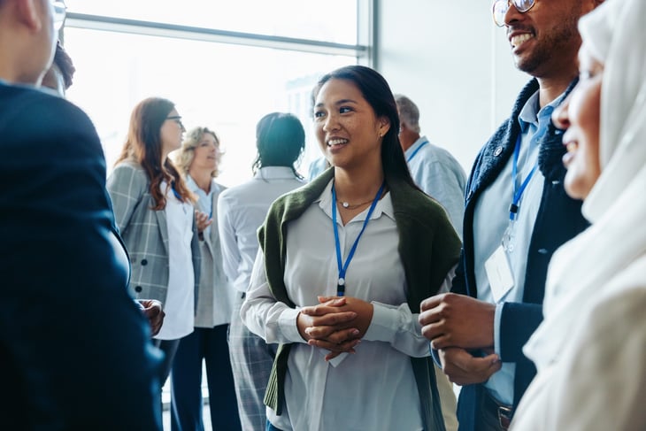 Group of diverse business professionals, talking and networking at a conference event.
