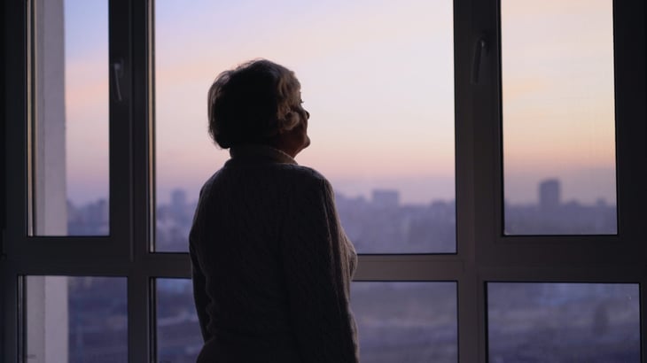 Lonely older woman looking out the window.