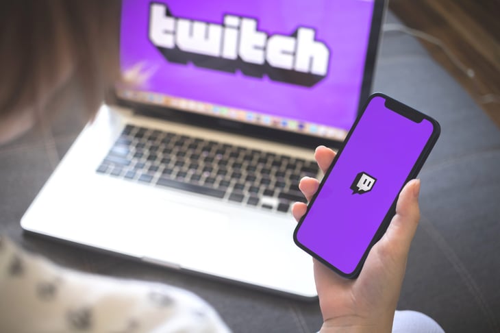 Twitch streaming app on a smartphone and logo on a laptop