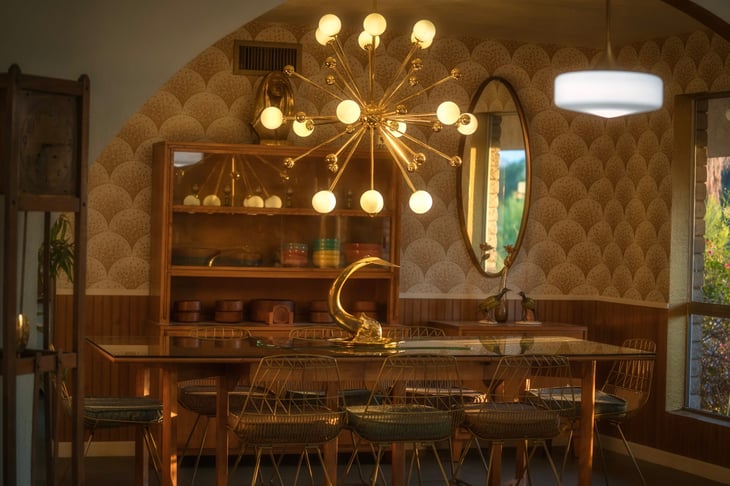 stylish mid century modern dining room with a long table, brass centerpiece, hutch