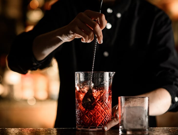 Bartender mixing drink with bar spoon.