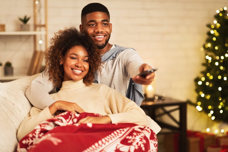 Happy couple watching TV at Christmastime.