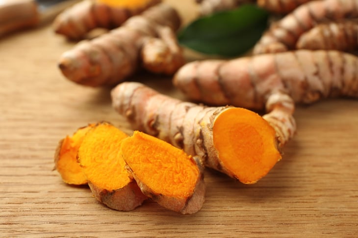 Cut turmeric roots on wooden table