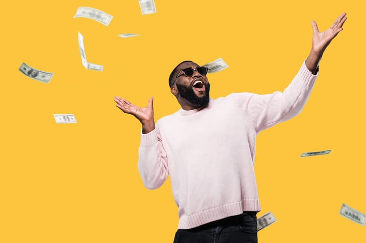 Man in glasses celebrating while it rains money