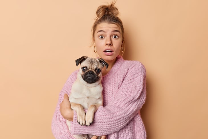 Shocked woman holding her dog.