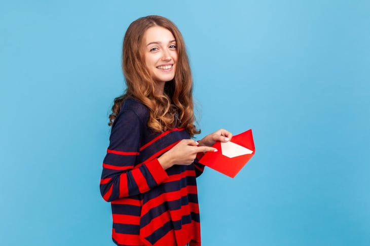 Woman holding open envelope with greeting card.