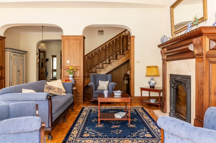 Living room interior with antique rug, sofa and coffee table in front of a fireplace in an English style mansion.