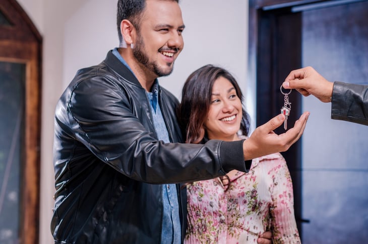 A sales agent gives a couple the keys to their new house