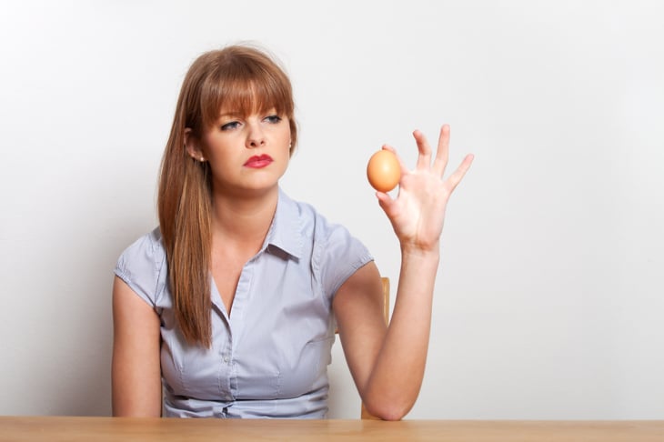 woman looking suspiciously at egg do I want to eat this