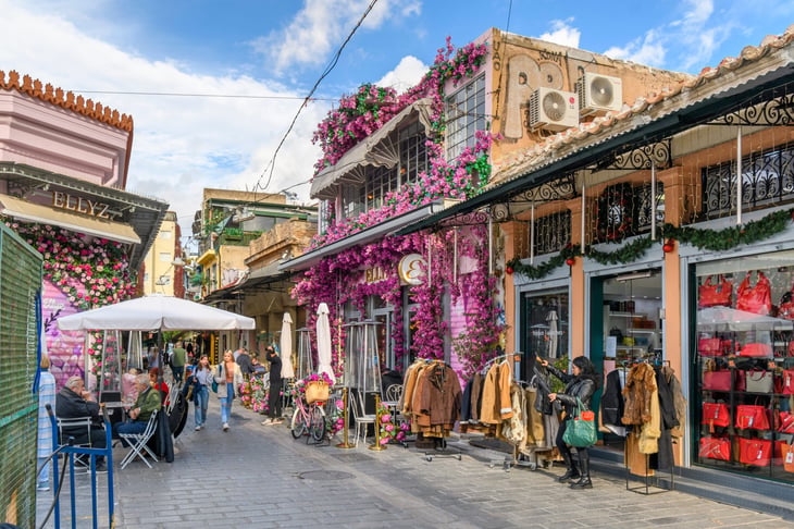A colorfully decorated shop and sidewalk cafe with pink and magenta flowers near the Monastiraki flea market in Athens, Greece.