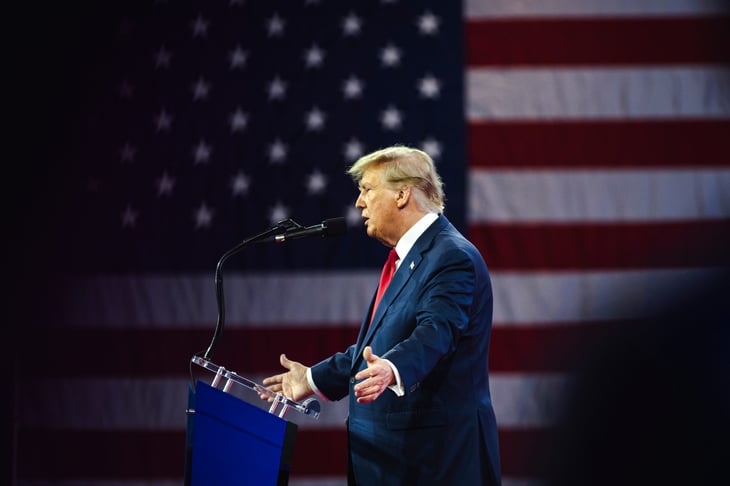 President Donald Trump speaking in front of an American flag