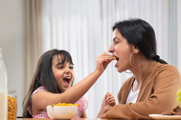 Happy daughter feeds mom cereal