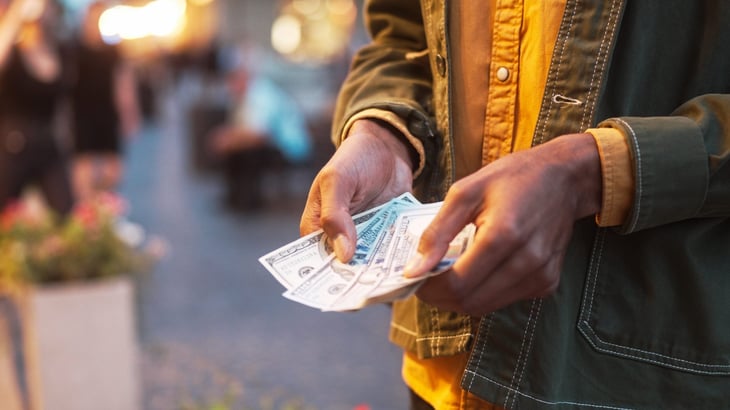 Man's hands holding cash, $100 bills