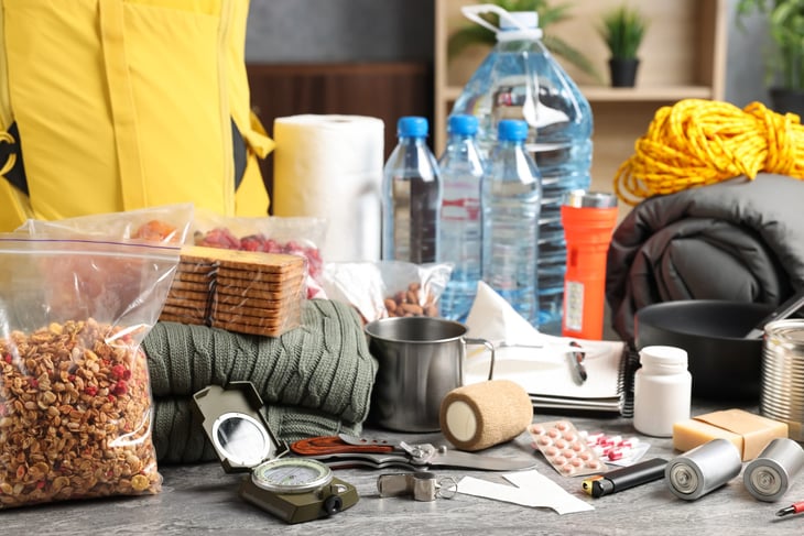Disaster or emergency supply kit with nonperishable food, flashlight, compass, bottle water, sleeping bag, bandages and more.