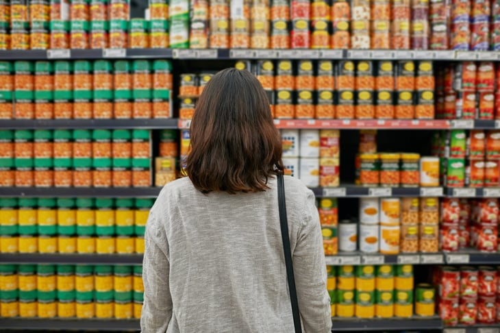 Woman grocery shopping for canned goods