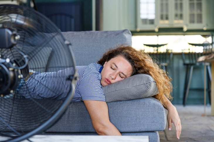 Woman sleeping with an electric fan nearby