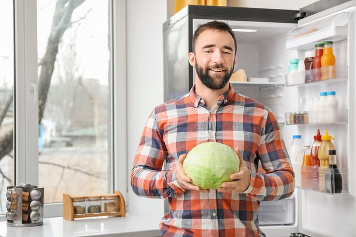 Man holding cabbage in kitchen