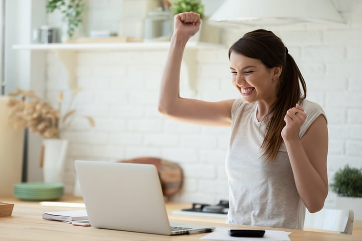 Happy woman working on her taxes at a laptop